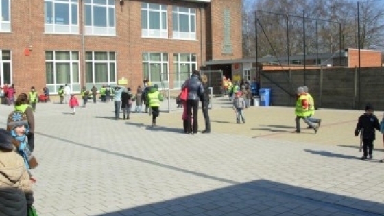 Foto van kinderen met hesjes die rondlopen en spelen op de speelplaats van de Wijnbergschool