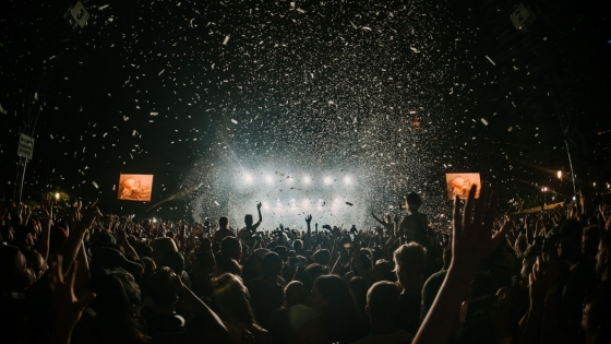 Afbeelding van duizenden mensen op een festival en met confetti die wordt afgevuurd.