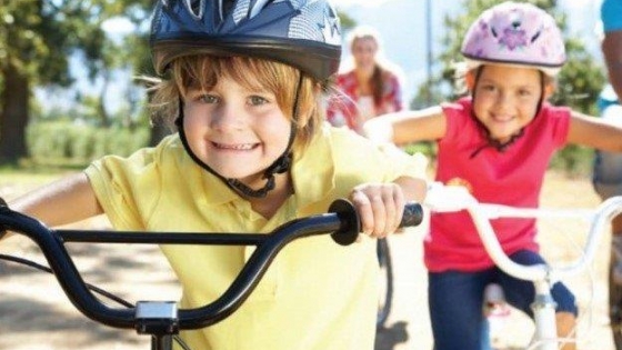 kinderen met blauwe en roze helm op de fiets