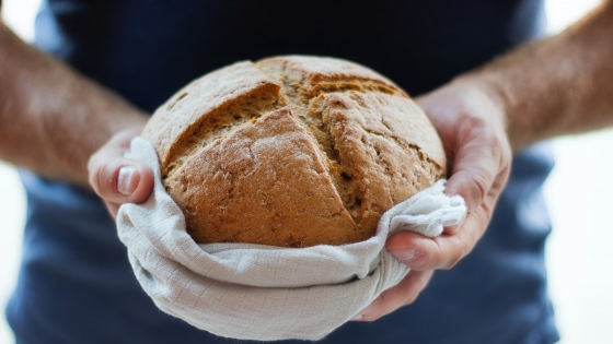 bakker houdt zijn versgemaakte ronde brood vast in zijn handen