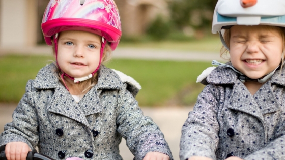 KIJK! Ik fiets! 2 kleine meisjes met helm en dezelfde fiets zitten op hun fiets 