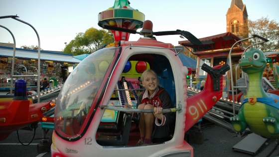 Foto van meisje in een helicopter op een atractie op de kermis