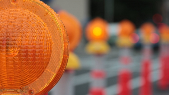 Foto van de oranje lichten op de rood met witte verkeerspaaltjes dat ze plaatsen als er wegenwerken zijn
