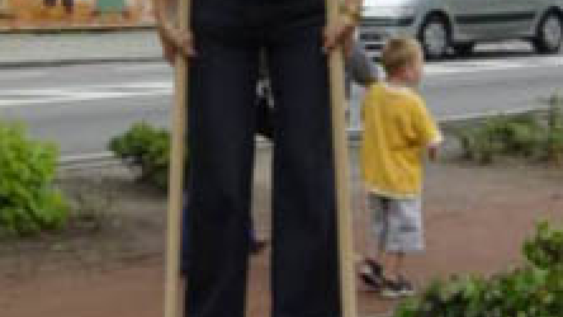 vrouw loopt op stelten met in de achtergrond een klein kind