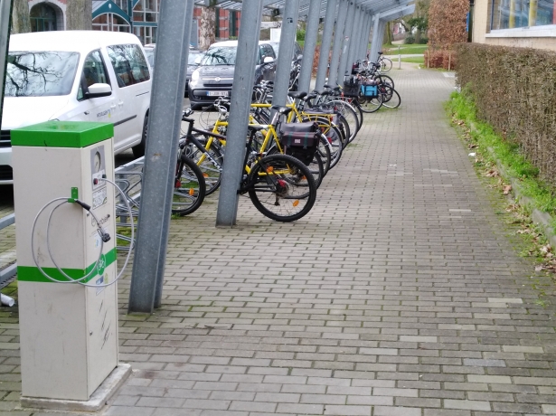 Fietspomp in groen en wit naast de overdekte opslagplaats voor fietsen