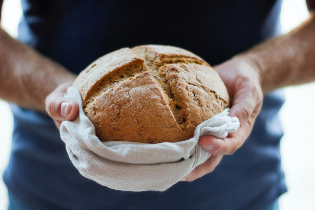bakker houdt zijn versgemaakte ronde brood vast in zijn handen